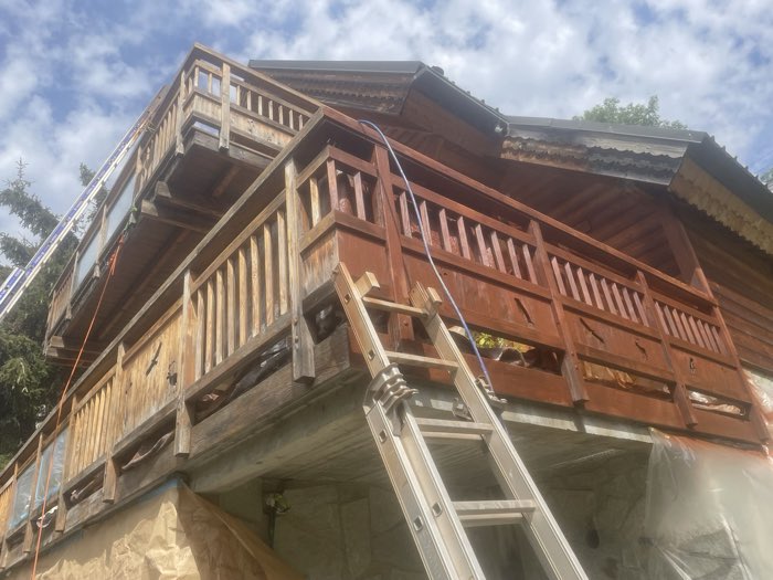 Balcon de chalet en bois en cours de rénovation, moitié décapée moitié lasurée