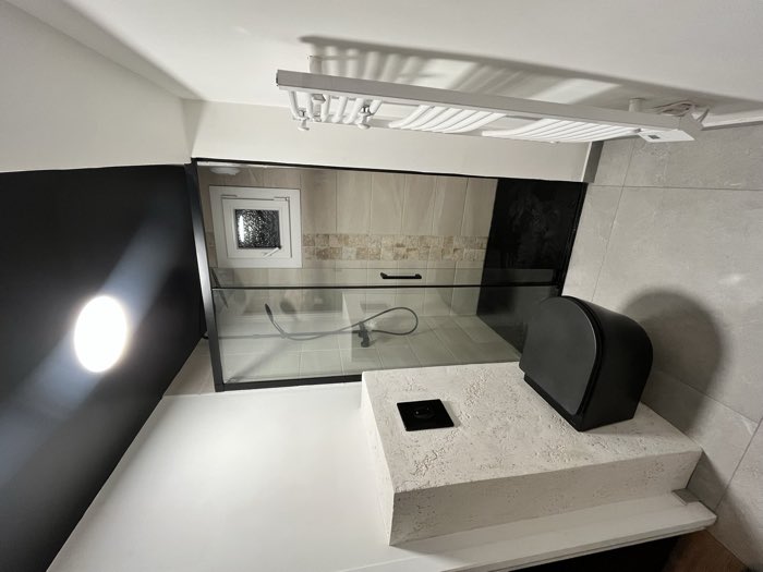 Salle d'eau rénovée : douche à l'italienne, plafond noir mat et parement pierre