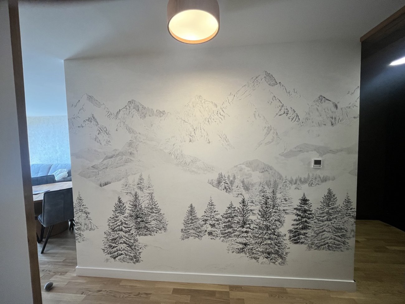Grand décor mural représentant un panorama de montagnes et de sapins dans un séjour